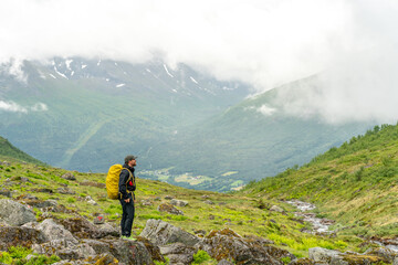 Fototapeta premium male hiker in the fjord of Andalsnes - Isfjorden in Norway hiking on a rainy cloudy day in the mountains of Massvassbu