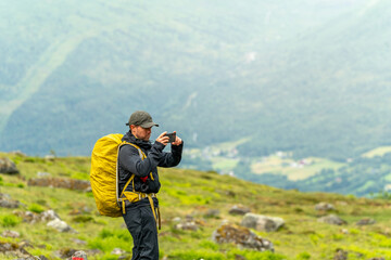 male hiker in the fjord of Andalsnes - Isfjorden in Norway hiking on a rainy cloudy day in the mountains of Massvassbu