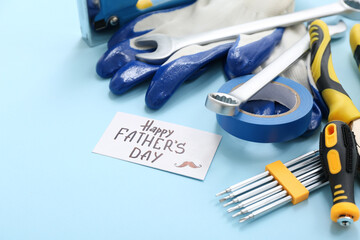 Tools and greeting card with text HAPPY FATHER'S DAY on blue background. Father's Day celebration