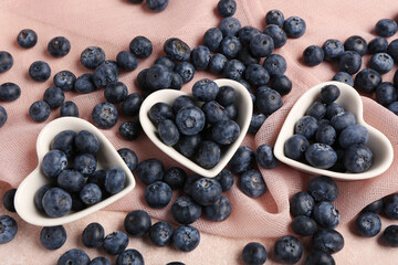 Bowls with sweet fresh blueberries on pink background
