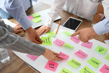 Business people working with sticky notes at table in office, closeup