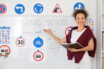 Female instructor with notebook near whiteboard at driving school