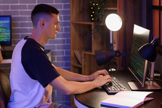 Young male programmer working with computer in office at night