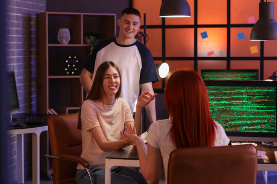 Team of young programmers working in office at night