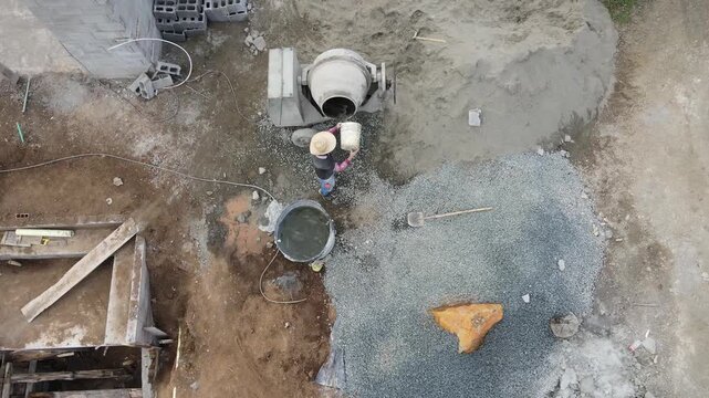 top aerial view of worker adding water to the concrete mixer in construction site