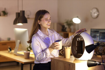 Young businesswoman making coffee in office at night