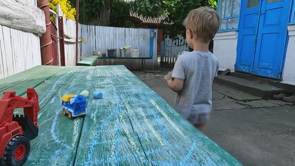 Boy near table with chalk and toy car model. Concept of concentration, attention, interest, creativity, skill, preschool education, drawing, entertainment, hobby, care, washing clothes, learning - Powered by Adobe