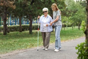 Blind senior woman with her granddaughter walking in park