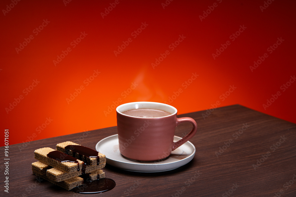 Wall mural the chocolate chip cookie biscuit with a cup of chocolate drink on a orange background.