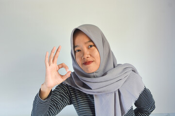 Young cheerful happy smiling pleasant successful employee business woman in her 20s wearing casual brown classic jacket showing okay okay gesture isolated on plain pastel light pink background studio