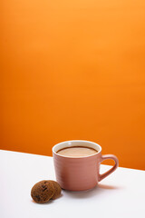 The chocolate chip cookie biscuit with a cup of chocolate drink on a orange background. 