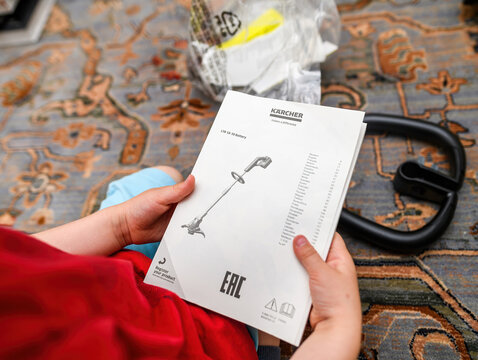 Paris, France - Jun 25, 2024: A toddler's hand holds the Karcher LTR 18-30 Cordless Grass Trimmer instruction manual, preparing to explore it with curiosity before the parent's first usage