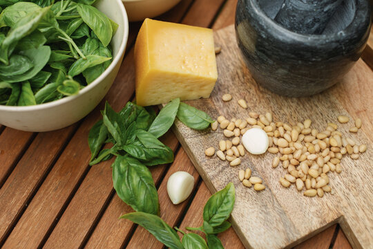 Close-up of basil, parmesan, pine nuts and olive oil on a table for making fresh basil pesto sauce