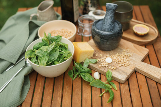 Close-up of basil, parmesan, pine nuts and olive oil on a table for making fresh basil pesto sauce