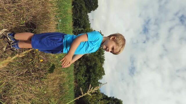 Vertical video- a sick child wipes his snotty nose with his fingers in nature. Treatment of snot in children. Concepts about health, colds, immunity, prevention, cleansing, flu, bacteria, handkerchief