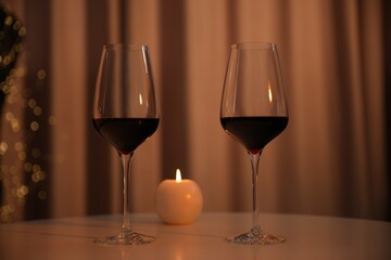 Burning candle and wine in glasses on table indoors