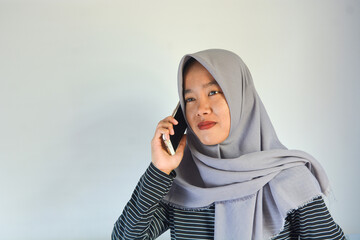 Portrait of an Asian woman holding a smartphone while smiling at the camera and raising her hand showing an okay gesture. on an isolated background