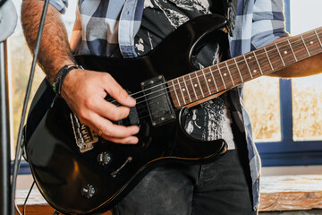Man playing electric guitar. Band rehearsing at home. International music day.