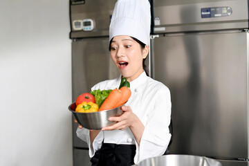 沢山の野菜を持ちながら驚く若い女性調理師