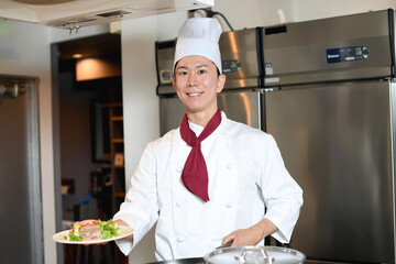 料理を提供する若いアジア人の男性調理師