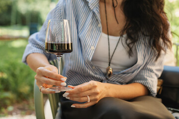 Close-up of a woman sitting on a terrace drinking a glass of red wine in summer