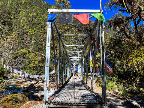 Rear view of a man crossing a metal footbridge, Jomolhari Base Camp trek (Chomholari trek), Jigme Dorje National Park, Bhutan