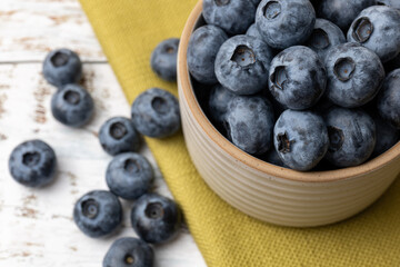 Close up of fresh blueberries in a bowl with green cloth.
