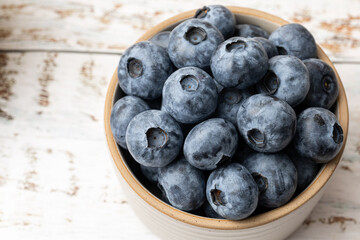 Close up of farm fresh blueberries in a bowl on a wooden table. 