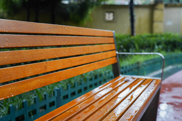 wooden bench standing on the sides of the paved paths of neighbourhood on a rainy day, Chengdu,...