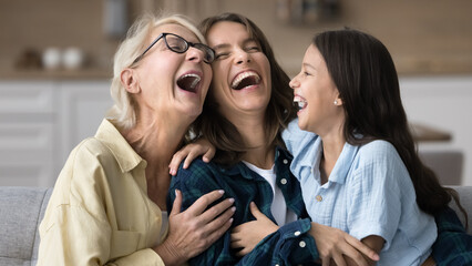 Excited grandma, happy young mother and cheerful kid girl laughing out loud with open mouth, having...