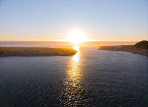 The sun is setting over the ocean, casting a warm glow on the water