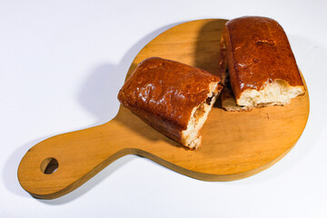 long sweet toast, which has been torn into two pieces on a wooden chopping board