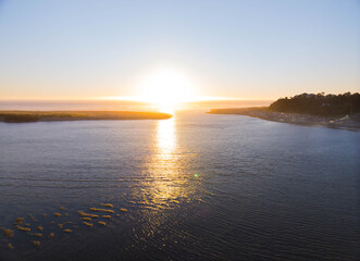 The sun is setting over the ocean, casting a warm glow on the water
