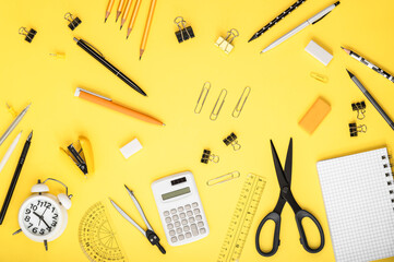 Stationery, notebooks, alarm clock and calculator on a yellow background. Back to school concept....