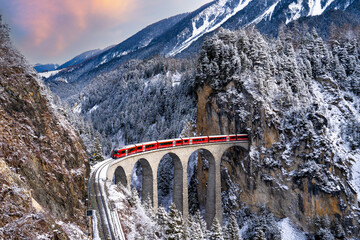 Train passes through snow-capped mountains in Filisur, Switzerland in the winter of the Swiss Alps.
