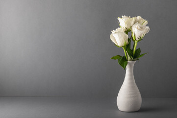 Bouquet of white roses in a small ceramic vase on a gray background. Floral background, mockup, congratulations with copy space.