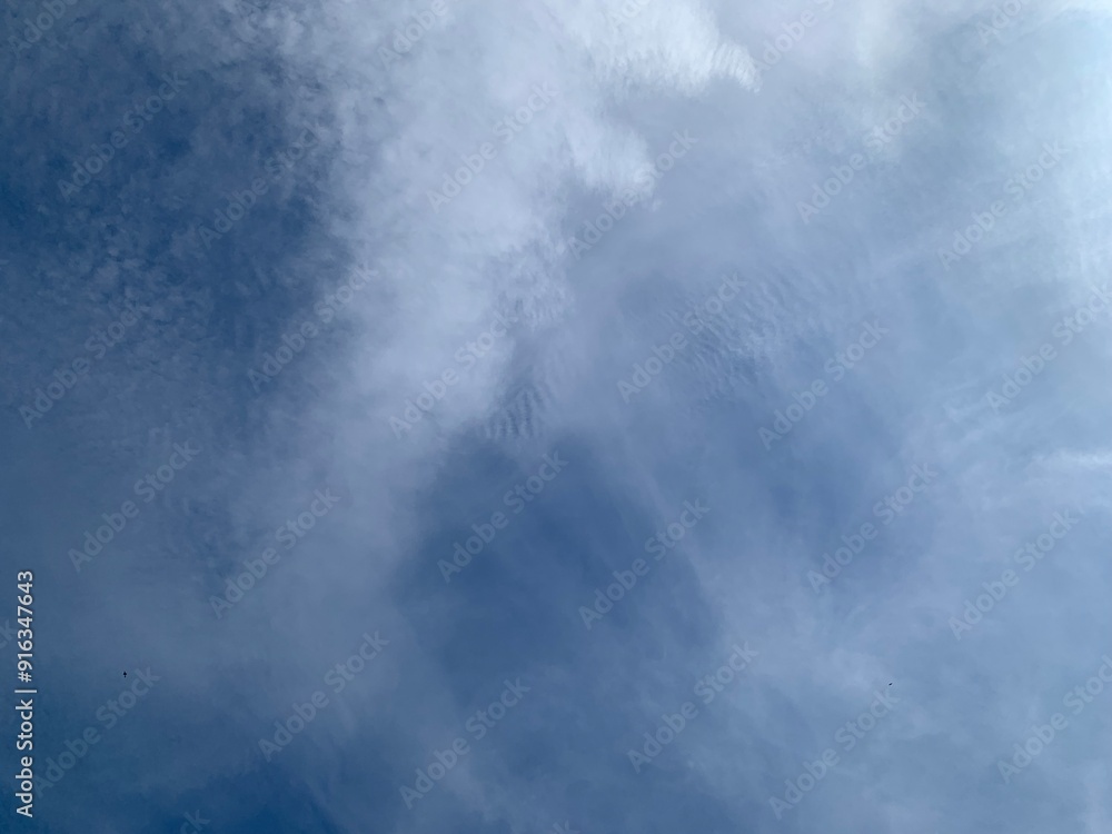 Wall mural an image of a sky with thinly scattered white clouds and bright light.