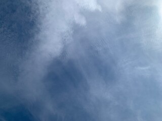 An image of a sky with thinly scattered white clouds and bright light.