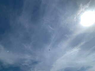 Image of a sky with white clouds and the bright light of the sun.