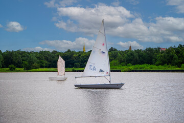 A small white sailboat floating in the middle of the water on a clear day during a holiday with water activities.
