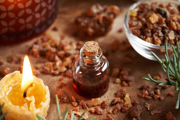 A glass bottle of essential oil with myrrh resin and bees wax candle