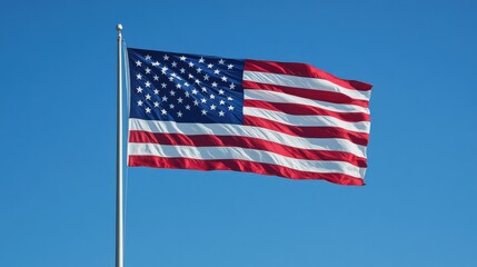 Obraz premium A close-up of an American flag waving in the wind against a clear blue sky, the stars and stripes clearly visible, symbolizing patriotism and freedom, evoking a sense of pride and national identity,