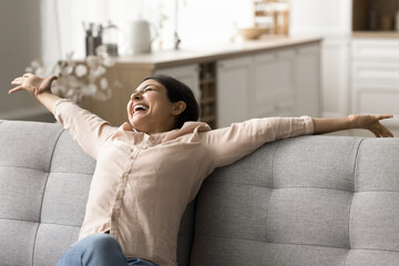 Woman relaxing on comfortable modern new bought couch, stretch her body, feels happy spend time on...