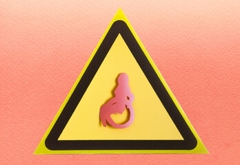 A warning sign with a close-up image of a man in a special chair in a yellow triangle.