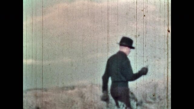 Cinematic killer making gun shot in natural field. Wild West bandit in criminal Western on nature background. Alone man in black clothes. Calm crime sociopath. Vintage color film. Retro 1960s archive