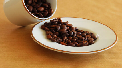Roasted coffee beans overflowing from a coffee cup