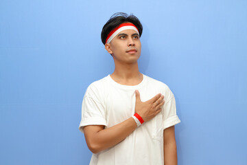 Indonesian man in white shirt and Indonesian flag posing proudly and saluting, Indonesian independence day concept