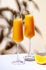 Summer orange cocktail drink with juice and dry champagne or sparkling wine. Beige background, hard light