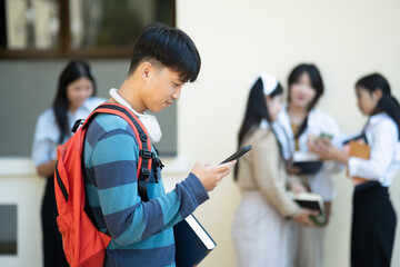Student using smartphone with friends in background