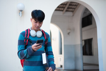 Student using smartphone while holding books on campus